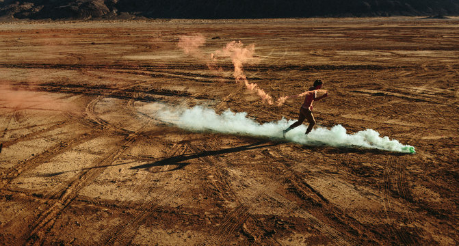 Young man running with Fireworks in the desert