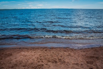 View of the lake, sky and clouds from the sandy shore.