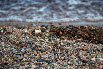 Many small stones on the shore of a clean lake.