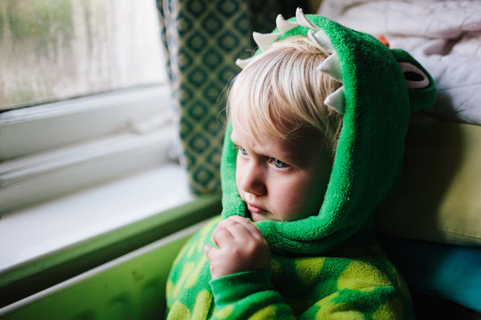 A little child dressed as a dragon taking some time out.