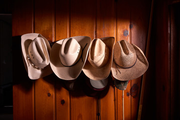 Four cowboy hats hung on wooden wall