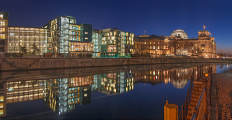 Berlin - Panorama of modern buildings on the riverside and Reichstag over the Spree river in evening dusk.