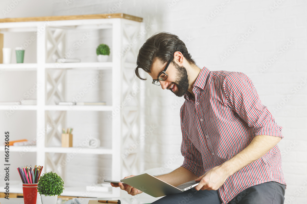 Wall mural Smiling businessman using laptop side