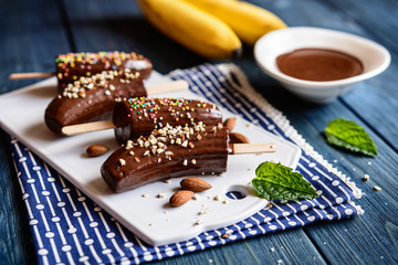 Bananas coated in chocolate and sprinkled with chopped almonds and colorful sprinkles