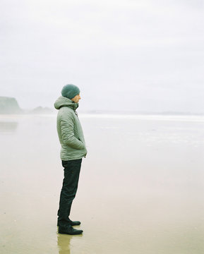 Man standing on a beach on a foggy winter day looking out to sea