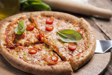 Italian pizza with tomato topped with melted golden cheese, herbs and basil