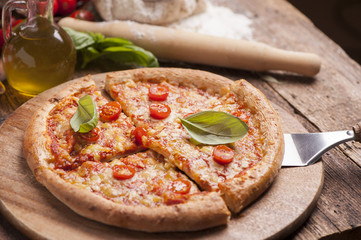 Italian pizza with tomato topped with melted golden cheese, herbs and basil