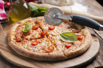 Italian pizza with tomato topped with melted golden cheese, herbs and basil
