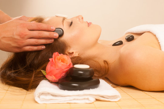 attractive young beautiful woman having facial massage with mineral stone
