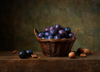 Still life with black plums in a basket on the table © Marta Teron