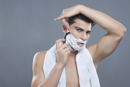 Portrait of young man shaving