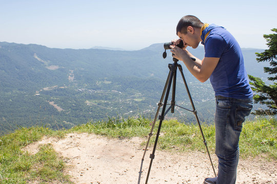 Traveller looking the nature from the high mountain with spotting scope, binoculars tripod