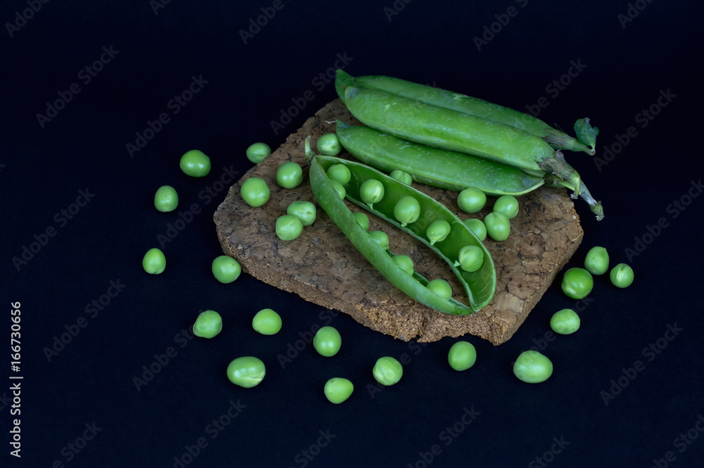 Wall mural pods of fresh green pea and individual peas on a black backgroun