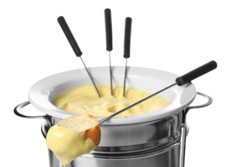 Cheese fondue in pot and piece of bread on stick against white background