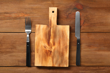 Board and cutlery on wooden background