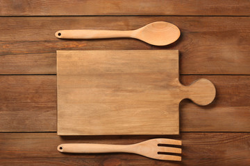 Board and utensils on wooden background