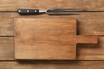 Board and meat fork on wooden background
