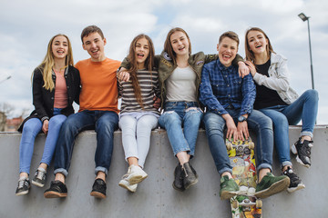 Summer holidays and teenage concept - group of smiling teenagers with skateboard hanging out outside.