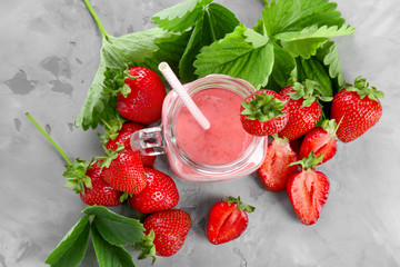 Delicious strawberry homemade smoothie in mason jar on grey background