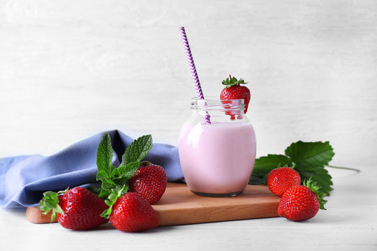 Jar of delicious strawberry homemade smoothie on cutting board