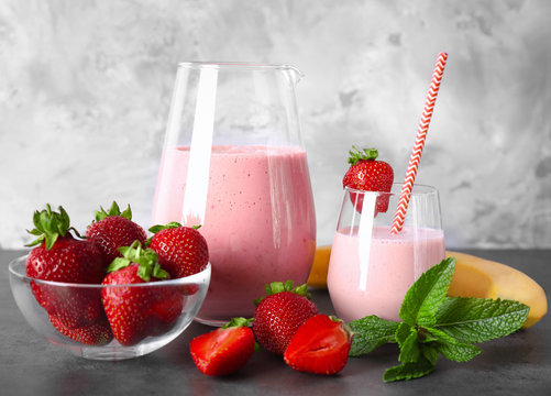 Strawberry and banana smoothie in glassware with ingredients on table