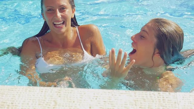 Cute girls playing laughing swimming in pool having fun smiling looking camera slow motion