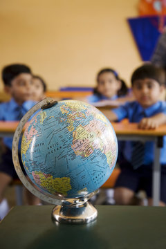 Globe on table with students sitting in background