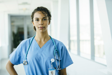 Portrait of confident, happy male nurse in hospital hallway