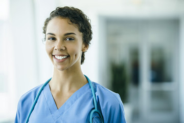 Portrait of confident, happy female nurse in hospital hallway