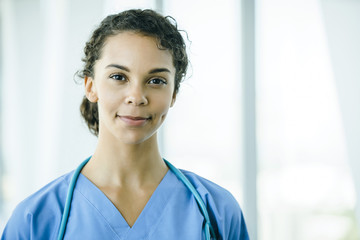 Portrait of confident, happy female nurse in hospital hallway