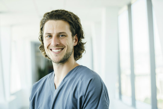 Portrait Of Confident, Happy Male Nurse In Hospital Hallway