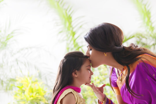 Woman kissing her daughters forehead 