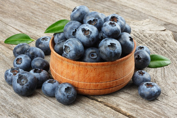 blueberries with green leaf in wooden bowl on old wooden table background