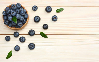 Naklejka na ściany i meble blueberries in wooden bowl on light wooden table background. top view with copy space