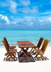 Wooden tables and chairs of tropical restaurant on the sand