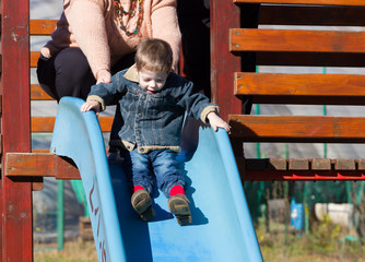 Fototapeta na wymiar child boy on a slide in a park in autumn