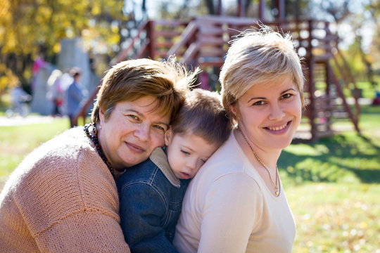grandmother, mother and son in a park in autumn