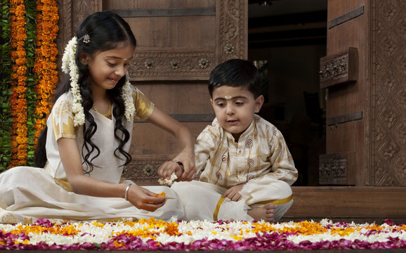 South Indian girl helping her brother with a rangoli 
