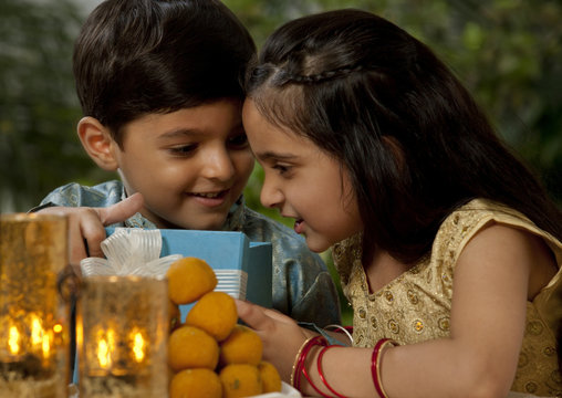Boy and girl opening gifts on Diwali 