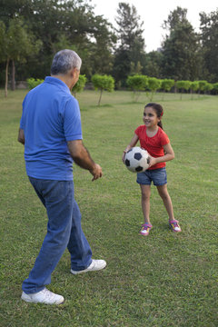 Grandfather and granddaughter playing with a football