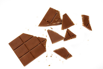 Broken tiles of milk chocolate on a white background, isolated. Copy space top view