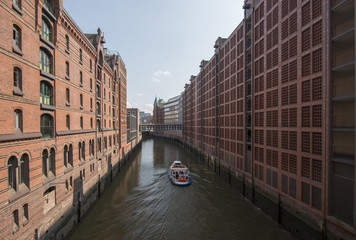 Eine Barkasse zwischen den Gebäuden der Speicherstadt Hamburg