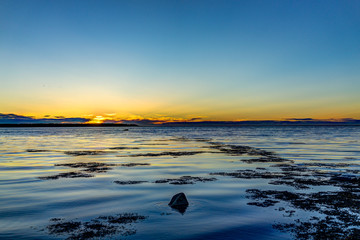 Fototapeta na wymiar Sunset in Rimouski, Quebec by Saint Lawrence river in Gaspesie region of Canada with seaweed