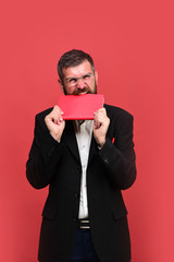 Man with beard and glasses bites red notebook