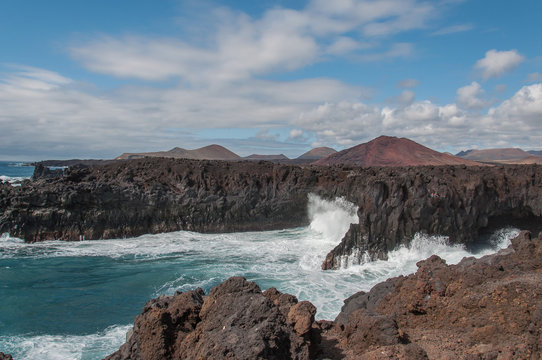 LANZAROTE, SPAIN - MAY 04, 2017: Tourists watching big fringing waves on Los Hervideros rocky coastline.Los Hervideros is a wonderful bay with intersting coast caverns