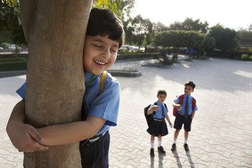 School boy hugging a tree 