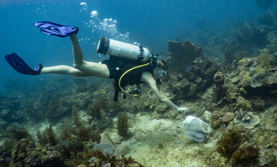 Female scuba diver collecting trash underwater