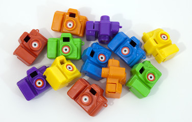Jumble of colorful inexpensive plastic toy cameras.