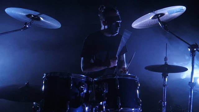 Concert rock band performing on stage with drummer in mask. Music video punk, heavy metal or rock group. Slow motion instrument playing