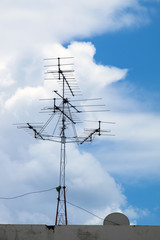 Antenna and satellite receivers, Television and satellite boardcating signal receiver in the beautiful blue sky with clouds.